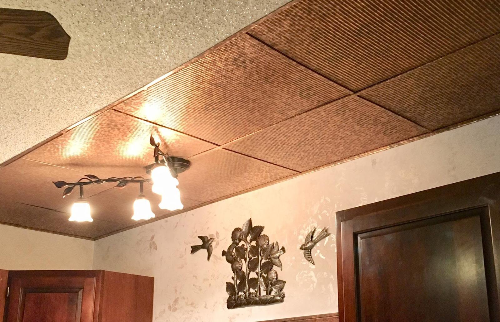 Copper-tone tin-look ceiling tiles with a branch light fixture