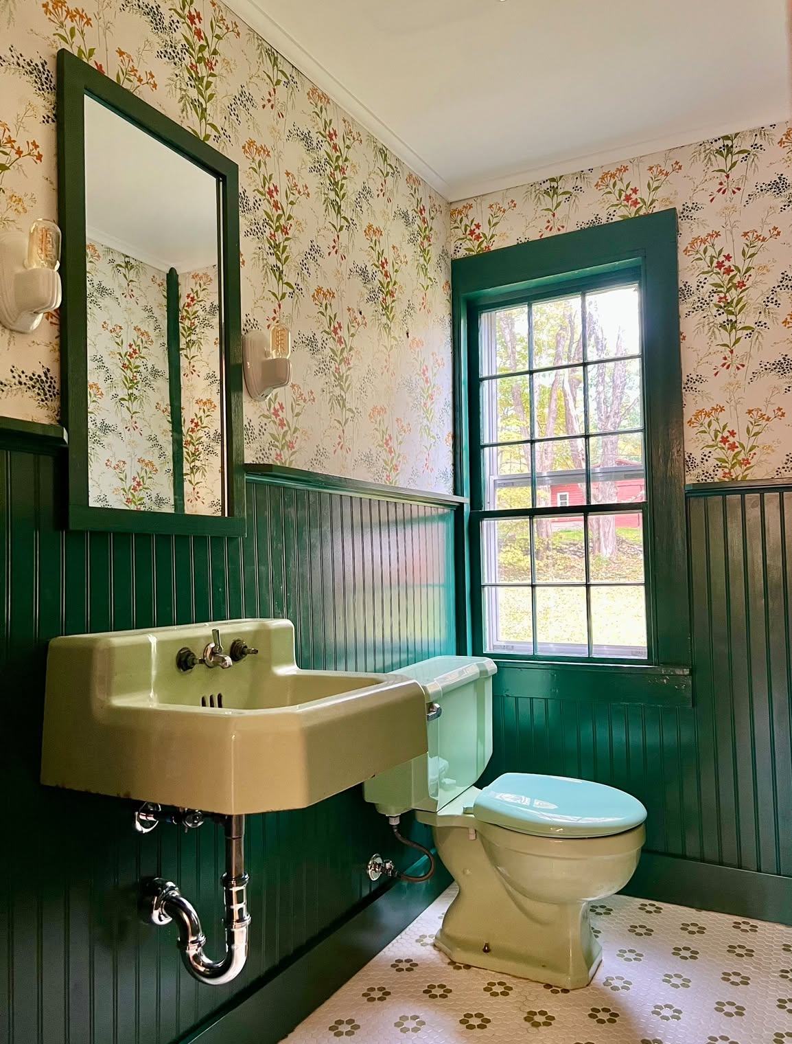 Bathroom with green beadboard, floral wallpaper and vintage pastel fixtures